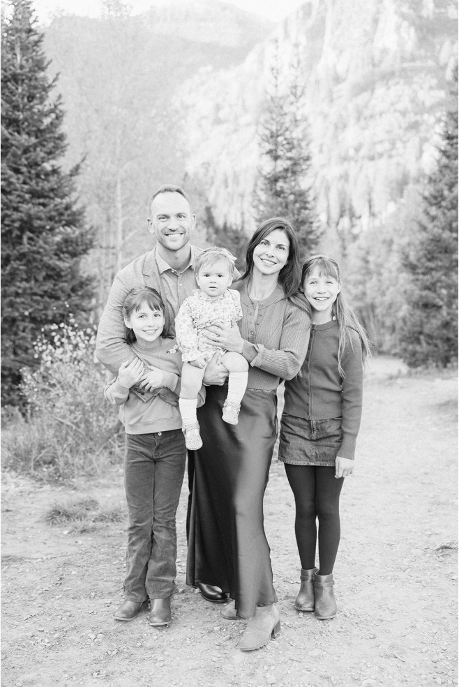 Black and white photo of a family of five standing on a trail with mountains behind