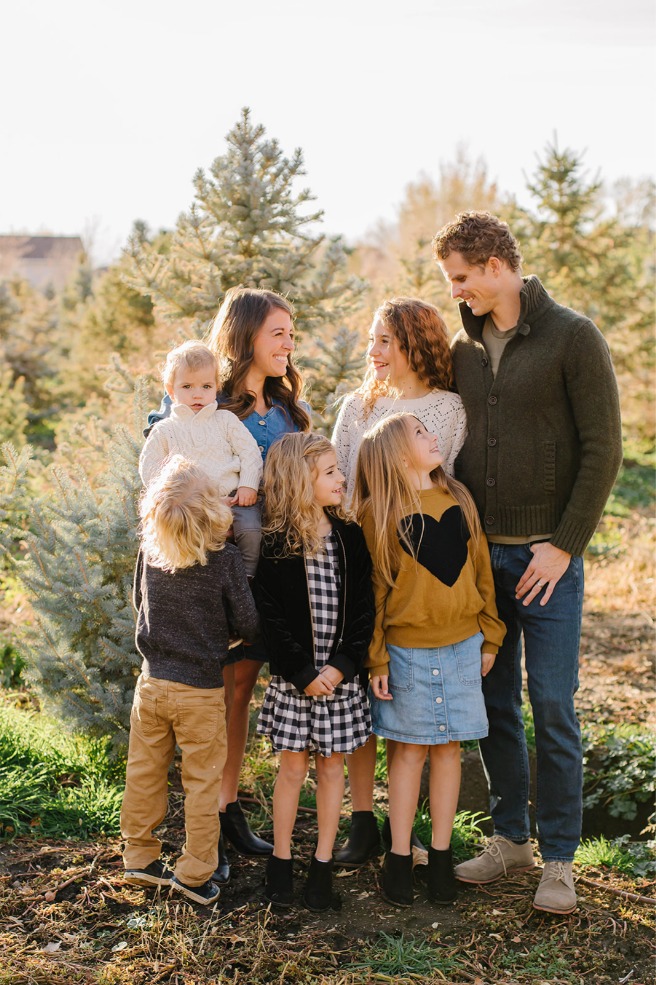 Family looking at each other in spruce rows during holiday photos