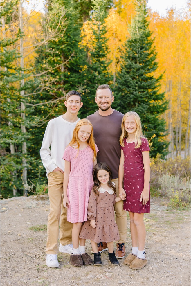 Family with a teen boy and three girls posed together in front of golden aspens in a Utah canyon