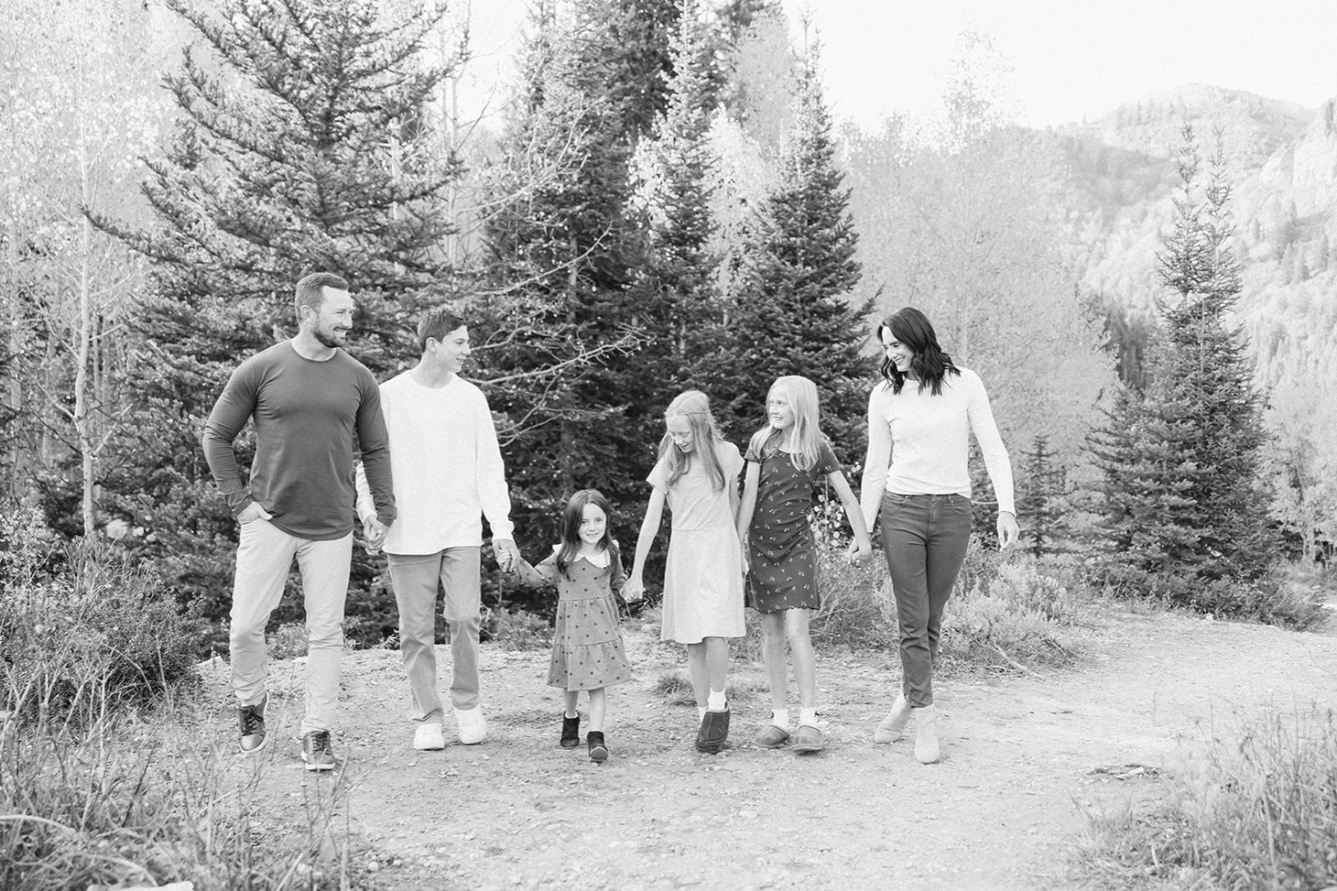 Black and white photo of a family walking hand in hand on a mountain trail