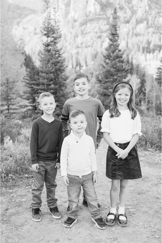 Black and white photo of four siblings grouped together outdoors in fall