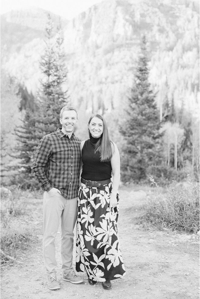 Black and white portrait of a mom and dad snuggled close on a mountain trail