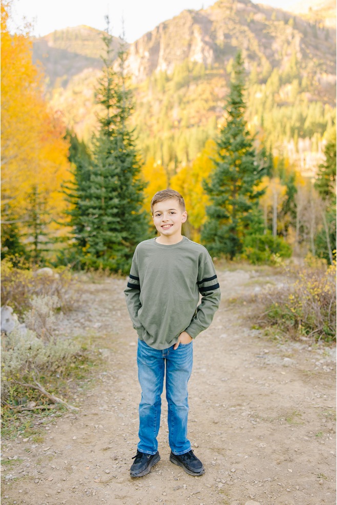 Full-length portrait of an older boy in green with a hand in his pocket on an aspen trail