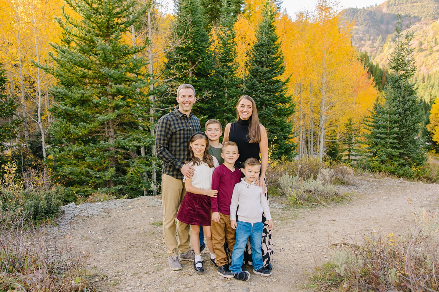 Family of six huddled close among peak golden aspens during fall family photos in Utah
