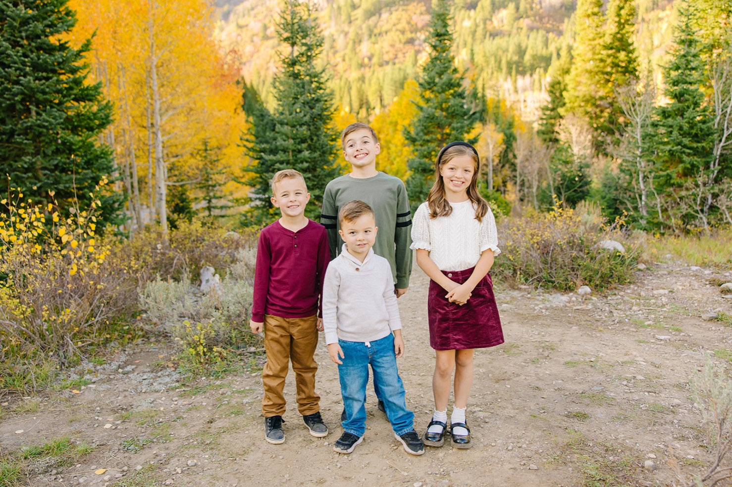 Four siblings standing together on a canyon trail lined with golden aspens