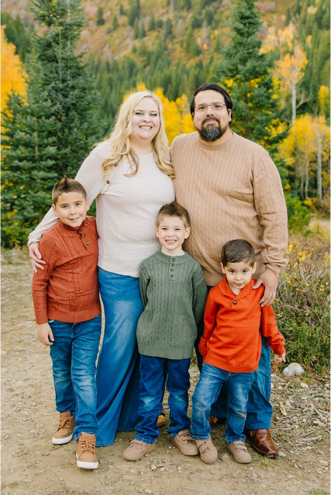 Mom and dad standing behind their three young sons in front of golden aspens and evergreens in a Utah canyon