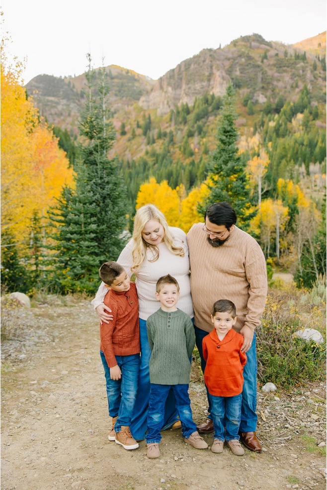 Family of five hugging and smiling with three boys in front and a golden aspen ridge behind