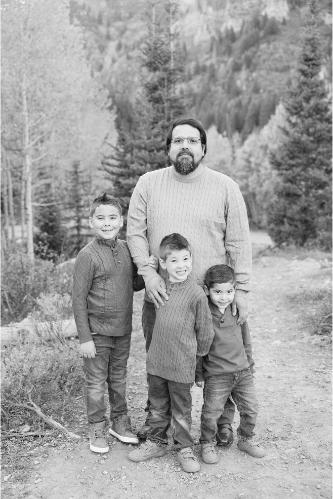 Black and white photo of a dad standing with his three sons on a mountain trail