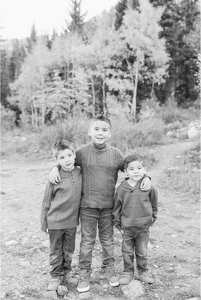 Black and white photo of three brothers with their arms around each other on a canyon trail