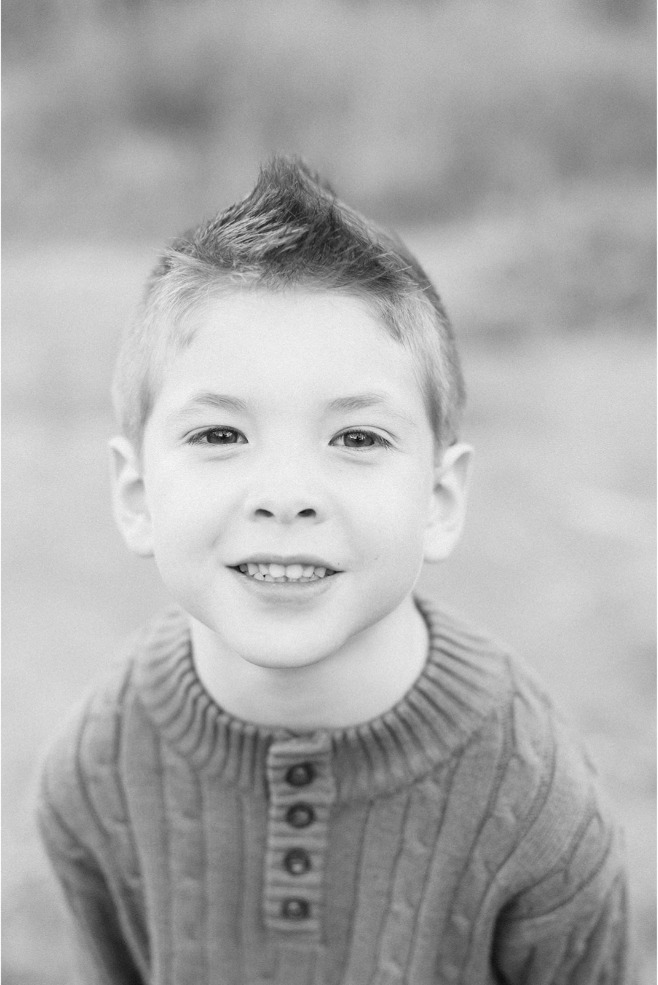 Black and white close-up portrait of a smiling boy in a ribbed sweater