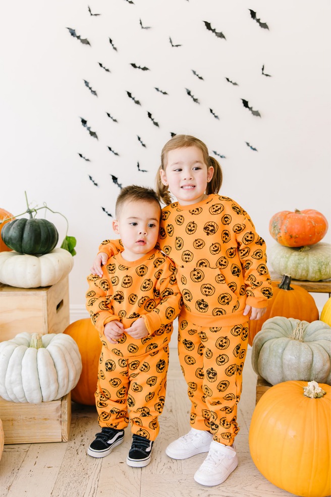 Brother and sister hugging in front of a paper bat backdrop at Halloween mini sessions in Utah