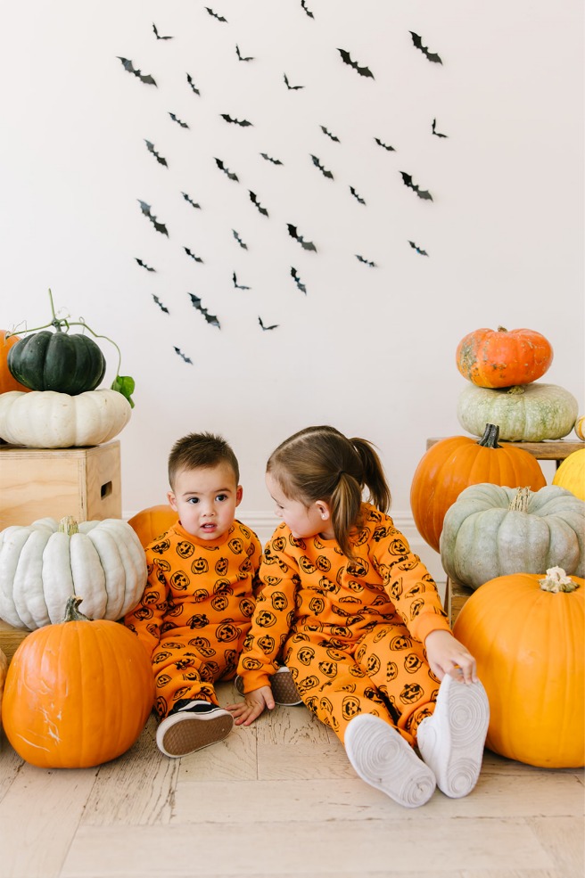 Siblings seated among pumpkins looking at each other during fall mini session photos